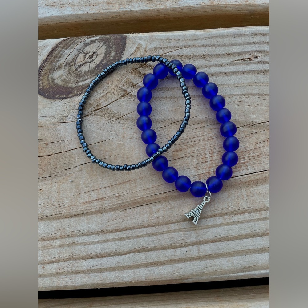 Two Paris theme beaded bracelets, one with a charm. Both blue and same size.